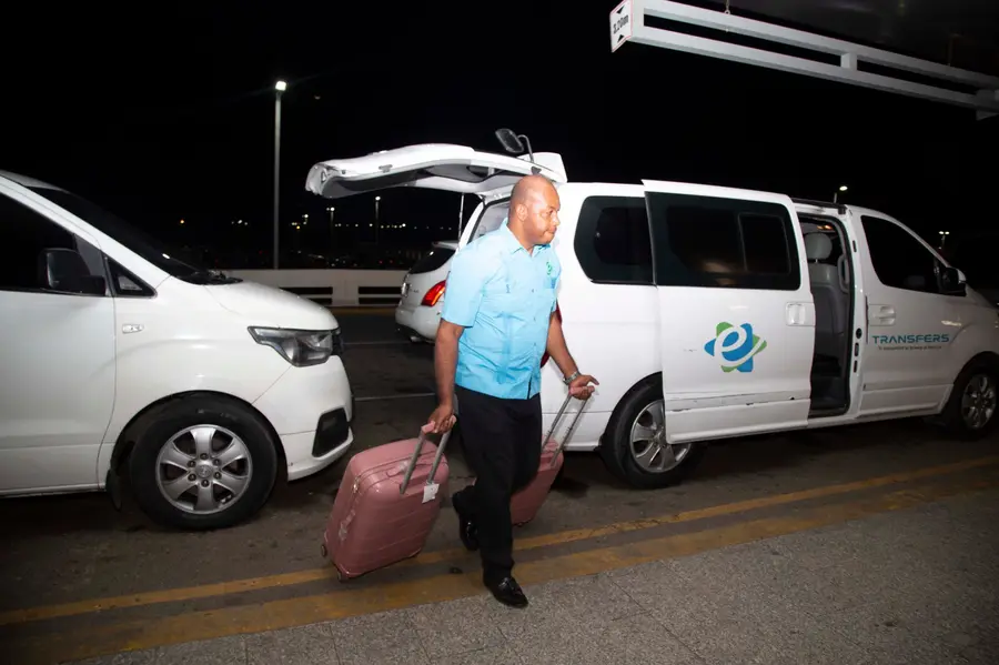 eTransferSDQ driver unloads clients' suitcases next to the minivan at the airport