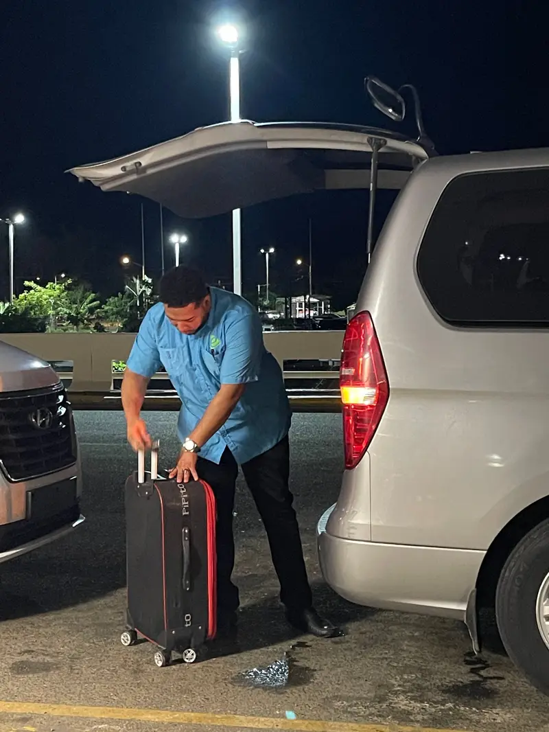 eTransferSDQ driver loads a passenger's suitcase into the minivan